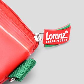 Das Lorenz-Logo der Crunchips hängt als kleines Schildchen am Reißverschluss einer Tasche.